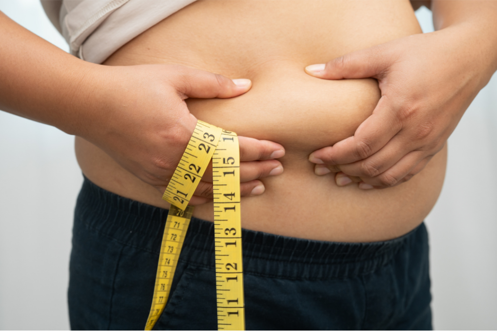 Adult measuring their waist with a tape: waist size is checked alongside BMI in medical weight management.
